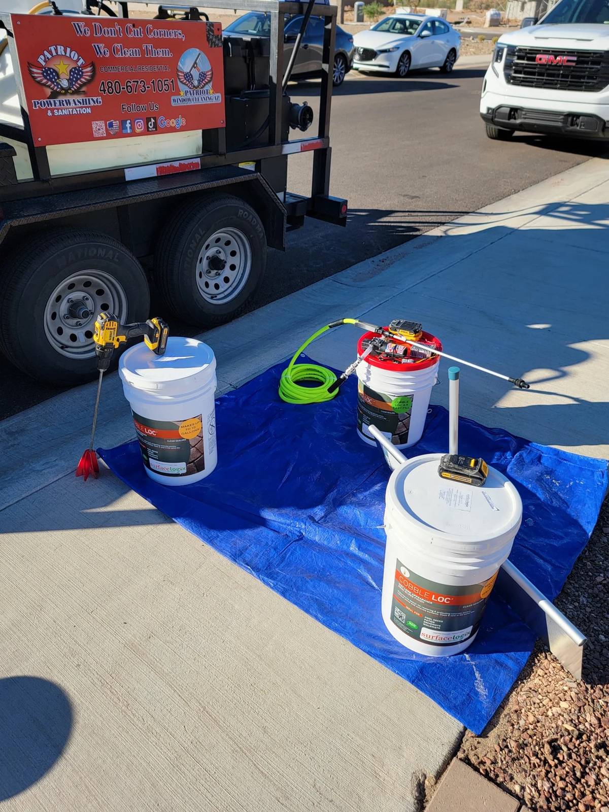 SurfaceLogix sealer buckets and Patriot spray equipment arranged on a protective tarp