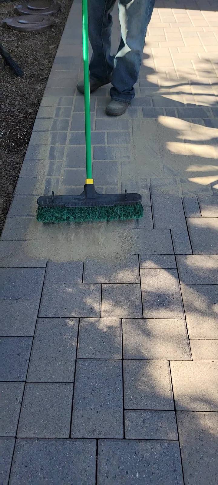 Sweeping joint sand into a paver driveway during preparation