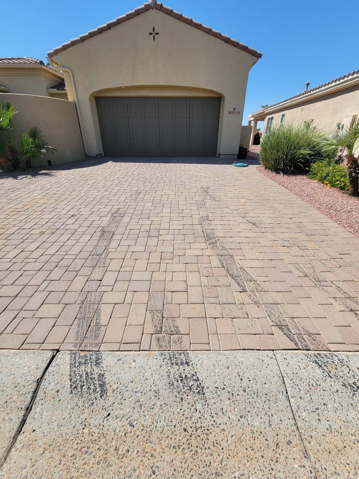 Paver driveway before cleaning with a contrasting concrete entrance