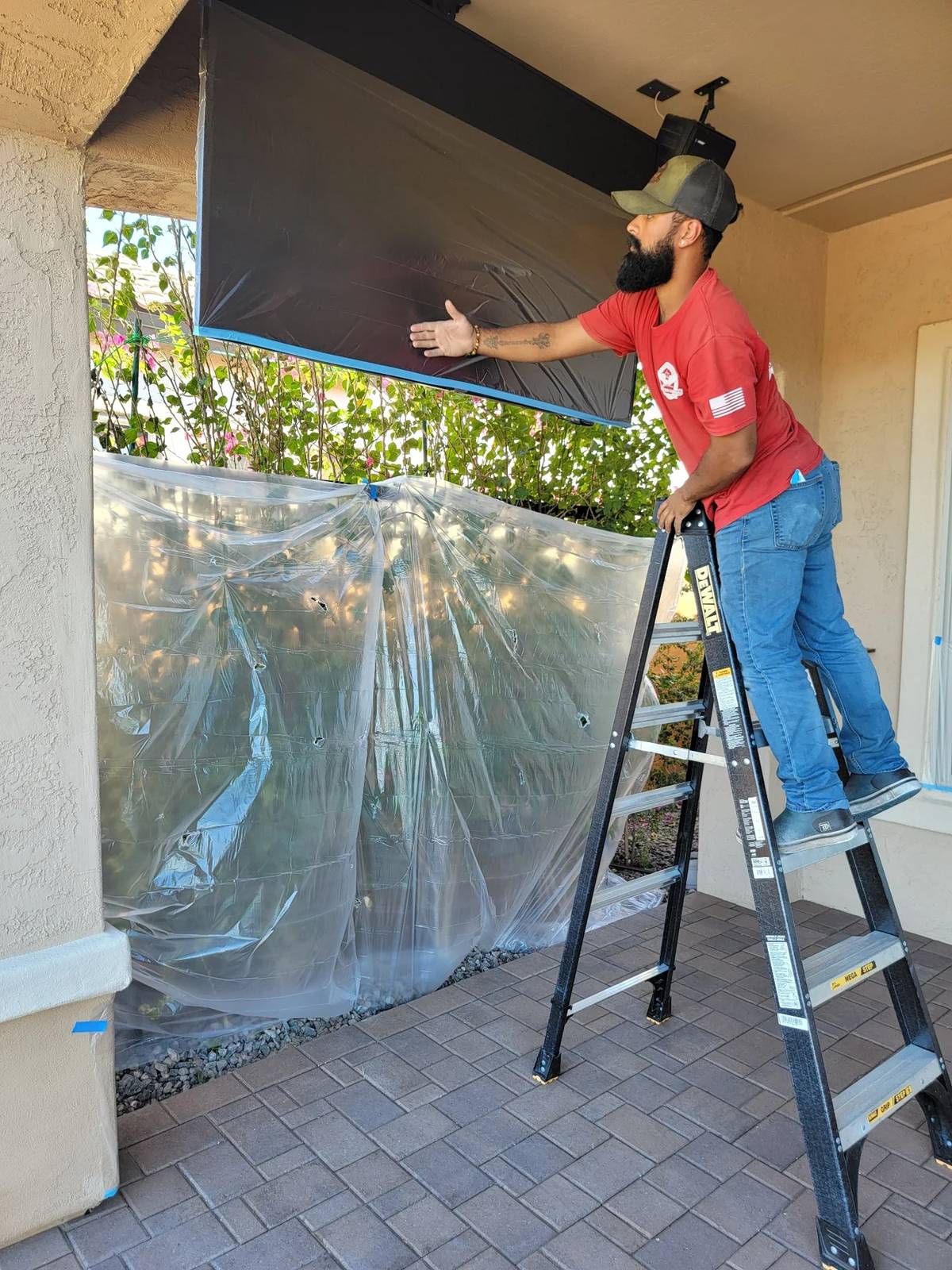 Patriot technician masking patio fixtures and nearby landscaping before sealing